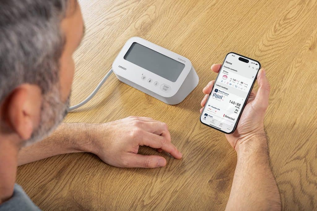 Photo d'un homme utilisant l'application Omron Connect avec son tensiomètre